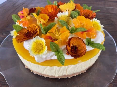 Rustic round sweet cake decorated with orange and yellow flowers, whipped cream  Stock Photos