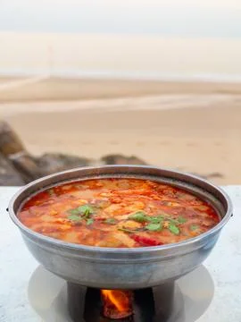 Rustic scene of chef making comforting tomato soup by beach at dusk Stock-Fotos