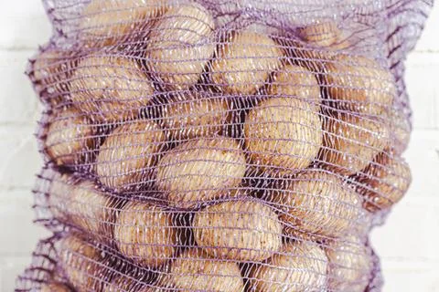 Rustic Scene of Fresh Potatoes in Mesh Bag on Wooden Table, Harvest Concept Stock Photos