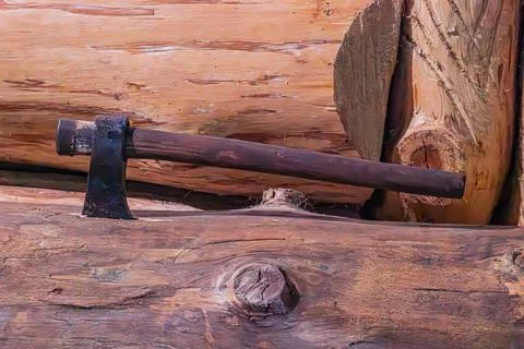 Rustic scene with large, freshly cut log and axe in foreground, unpeeled lo.. Stock Photos