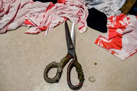 Rustic scissors on a table surrounded by colorful fabric pieces Stock Photos