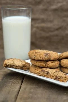 Rustic setting with chocolate chip cookies and glass of milk Stock Photos