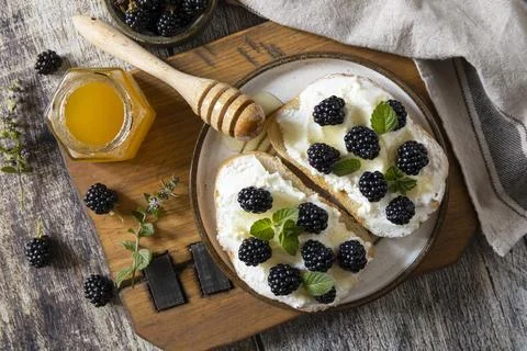 A rustic setting features a wooden board with slices of toast topped with cre Stock Photos