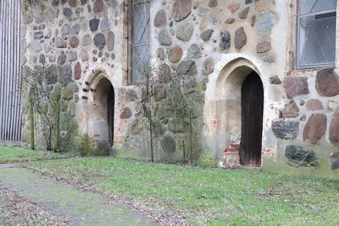 Rustic setting with historic stone wall, arched doors, charming ancient Stock Photos
