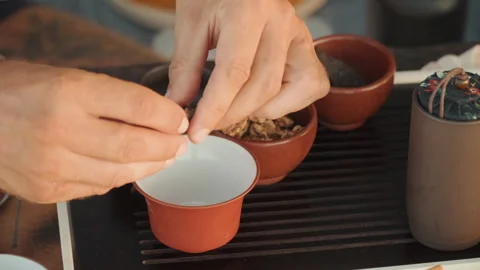 Rustic setting for mindful tea brewing process. Detailed view of artisan pouring Stock Footage 333568537