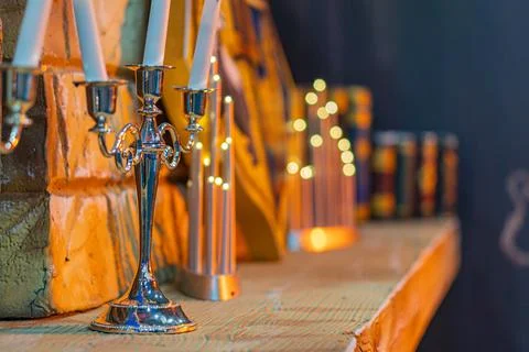 Rustic shelf with candlesticks, decorative elements, and small metallic figur Stock Photos