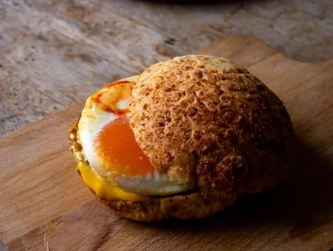 Rustic sourdough bread roll sandwich with sunny side up fried egg and melte.. Stock Photos