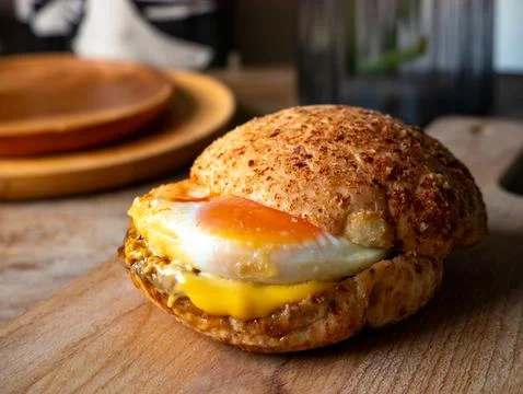 Rustic sourdough bread roll sandwich with sunny side up fried egg and melte.. Stock Photos