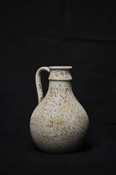 Rustic speckled ceramic jug with handle on black background Photos