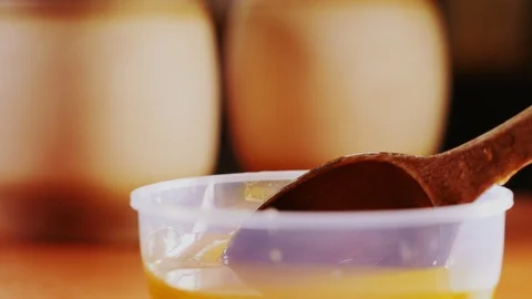 Rustic spoon with pouring honey over plastic bowl close view Stock Footage 123490805