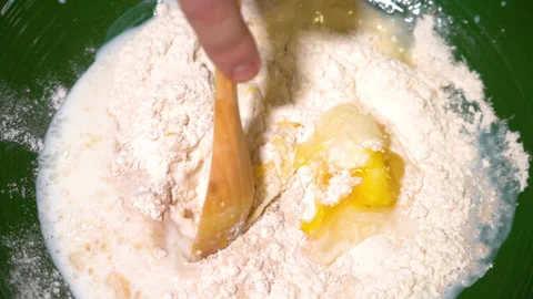 Rustic spoon whips egg yolk and flour in a bowl close up view Stock Footage 249173614