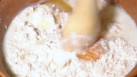 Rustic spoon whips egg yolk and flour in a bowl close up view Stock Footage 249513479