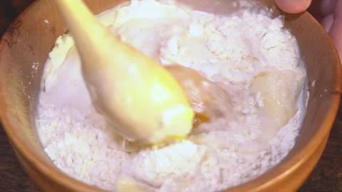 Rustic spoon whips egg yolk and flour in a bowl close up view Stock Footage 254167473