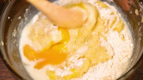 Rustic spoon whips egg yolk and flour in a bowl close up view Stock Footage 255398671