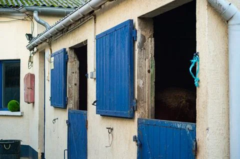 Rustic Stable Building with Vibrant Blue Doors and Gutters Stock Photos