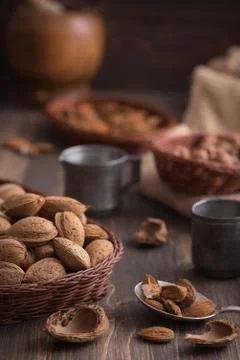 Rustic still life of almonds in the wicker plate on the dark rustic wooden ba Stock Photos