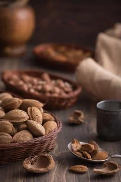Rustic still life of almonds in the wicker plate on the dark rustic wooden ba Stock Photos