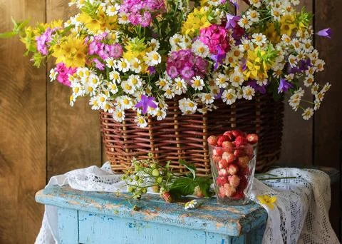 Rustic still life arranging a wicker basket of colorful wildflowers and a g.. Stock Photos