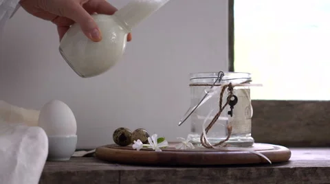 Rustic still life. female hand is pouring milk from a bottle into a glass jar Stock Footage