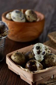 Rustic still life with quail eggs in bucket, box and bowl on a linen napkin over Stock Photos