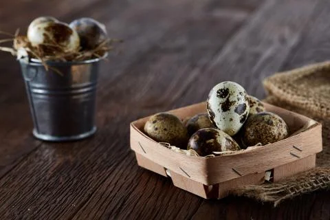 Rustic still life with quail eggs in bucket, box and bowl on a linen napkin over Stock Photos