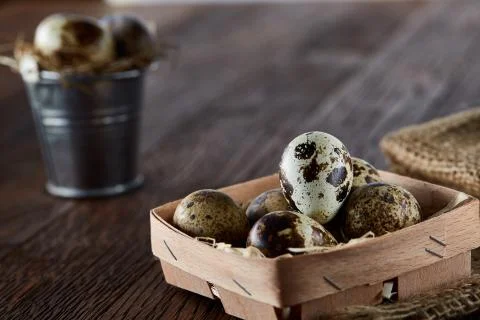 Rustic still life with quail eggs in bucket, box and bowl on a linen napkin over Stock Photos