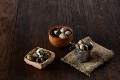 Rustic still life with quail eggs in bucket, box and bowl on a linen napkin over Stock Photos