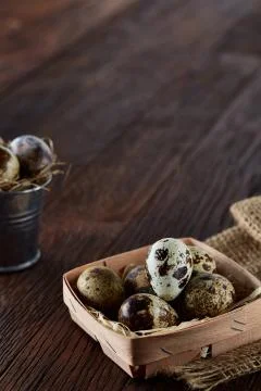 Rustic still life with quail eggs in bucket, box and bowl on a linen napkin over Stock Photos