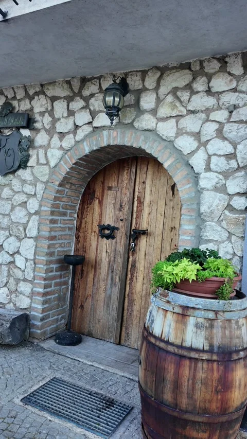 Rustic stone building facade with arched wooden doors and barrel detail Stock-Footage 341526323
