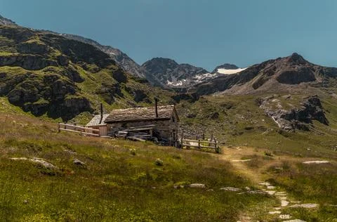 Rustic Stone Cabin on Sunny Alpine Hiking Trail with Glaciers and Mountain .. Stock Photos