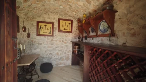 Rustic stone cellar with wine rack, ship plates, and copperware Stock Footage 327013603