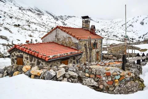 Rustic stone house in the middle of the mountains covered with snow Stock Photos