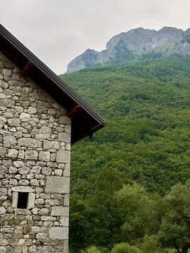 Rustic stone house surrounded by lush green forest and mountain scenery Stock Photos