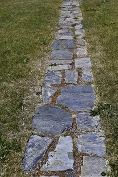 A rustic stone pathway laid out in a straight line across a grassy lawn Foto stock
