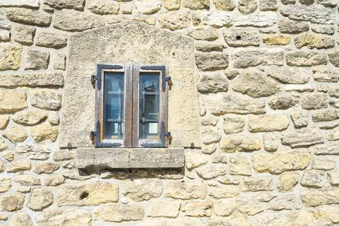 A rustic stone wall features a simple wooden-framed window in San Marino Stock Photos