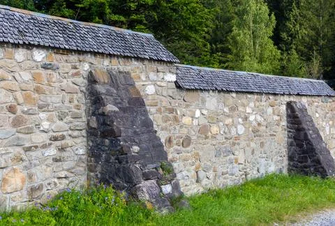 A rustic stone wall featuring prominent buttresses for structural support Stock Photos