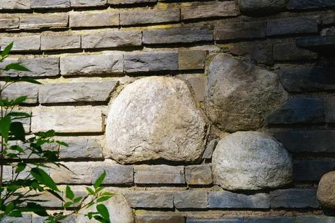 Rustic stone wall with large natural rocks embedded in layered brick constr.. Stock Photos
