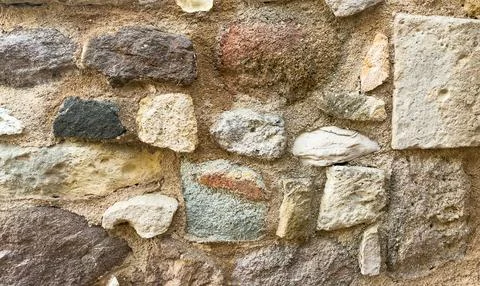 Rustic stone wall made of irregular blocks in different colors and textures Stock Photos