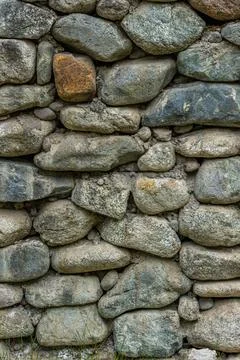Rustic stone wall made of various rocks outdoors in nature Stock Photos
