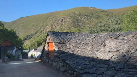 Rustic stone wall with orange door against green hillside 스톡 동영상 337186707