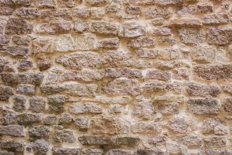 A rustic stone wall showcases irregular masonry, visible wear, and contrast.. Stock Photos