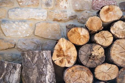 Rustic Stone Wall with a Stack of Firewood Logs Stock Photos
