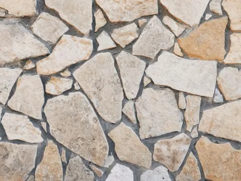 Rustic stone wall texture with irregular patterned rocks in earthy tones Foto stock