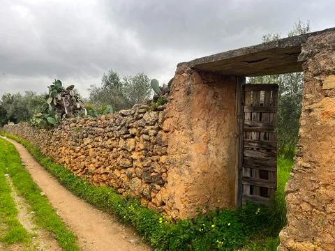Rustic Stone Wall with Wooden Gate Along Countryside Path Under Cloudy Sky Stock Photos