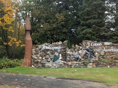 A rustic stone “Welcome to Cave Junction” sign with bear sculpture Stock Photos