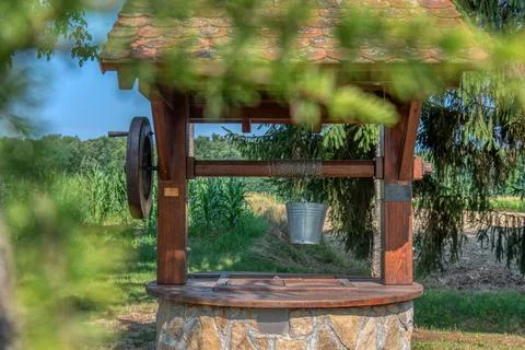 Rustic stone well with bucket and drinking water. Photos