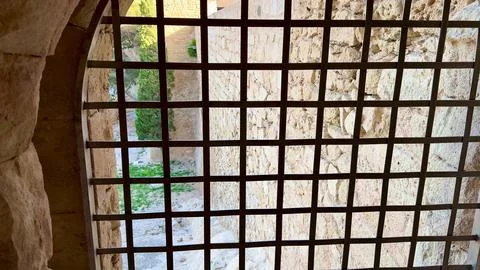 A Rustic Stone Window Framed by a Metal Grate, Offering a Beautiful View of.. Stock Photos