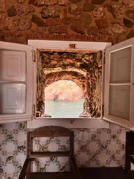 Rustic stone window with open shutters framing ocean view Stock Photos