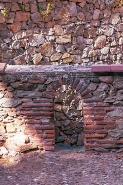 Rustic stonework features a weathered arch surrounded by a mix of stones in.. Foto stock