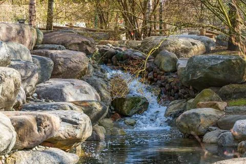 Rustic stream cascades over mossy stones Stock Photos